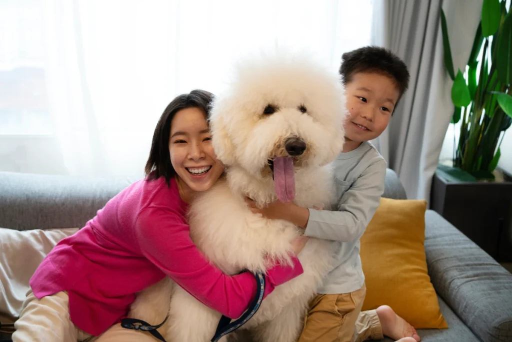 front view of brother and sister hugging big white hairy dog